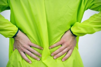 a young caucasian sportsman wearing sport clothes with his hands in his back because of his low back pain